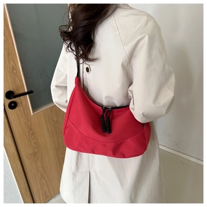 Détail d'un sac demi-lune rouge avec tirette de fermeture tressée noire et bandoulière