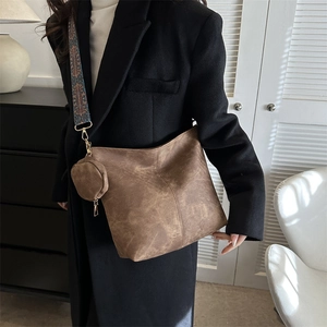 Grand sac fourre-tout marron vintage avec sangle tissée et pochette sur manteau noir
