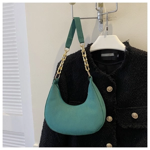 Detail of dark green hobo bag featuring gold chain and wide fabric shoulder straps