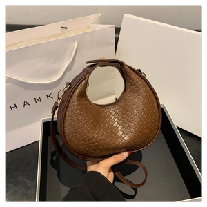 Dettaglio della trama in pelle intrecciata marrone e forma a mezzaluna della borsa moda