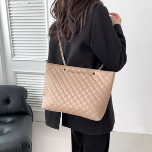 Borsa tote trapuntata beige con tracolla a catena indossata da modella in interno moderno