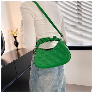 Detail of lime green crescent bag with quilted pattern and ruched handle worn by model