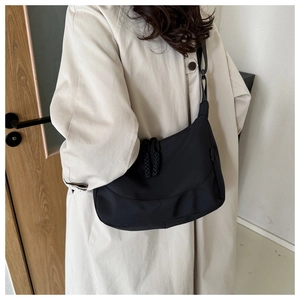 Détail du sac demi-lune en nylon noir imperméable avec bandoulière réglable et tirette tissée
