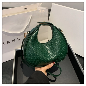 Dettaglio della borsa a mezzaluna intrecciata verde scuro con texture in pelle