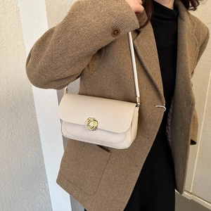 Sac à bandoulière en cuir beige minimaliste avec boucle dorée sur blazer en tweed