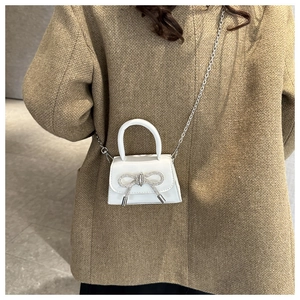 Detalle del mini bolso blanco con lazo de diamantes de imitación plateados y cadena de metal
