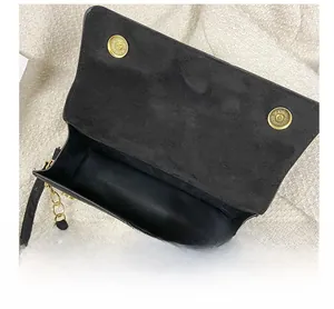 Detail der schwarzen Wildleder-Schultertasche mit Doppelmagnetverschluss und Goldkette