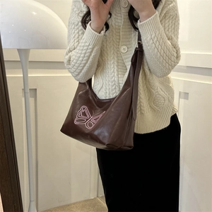 Brown leather tote bag with pink butterfly embroidery shown on casual white sweater outfit