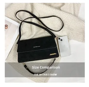 Mattschwarze Schultertasche im Größenvergleich mit Smartphone auf weißem Strick
