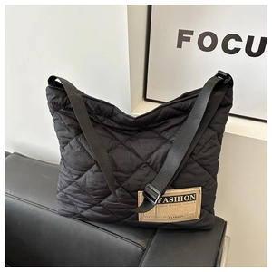 Détail du sac fourre-tout en nylon matelassé noir avec motif de losanges et étiquette