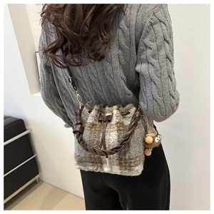 Detail of wool plaid bucket bag with braided leather handle and plush charm