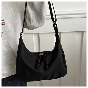 Détail du sac demi-lune en nylon noir avec tirettes tissées et étiquette latérale chic