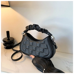 Detail of black pebbled leather texture with square embossing and pleated handle