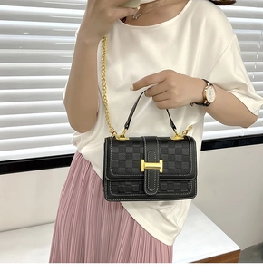 Détail du sac à rabat noir avec gaufrage en damier, boucle H dorée et bandoulière chaîne