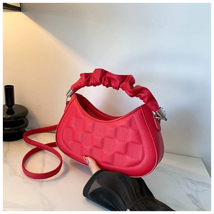 Close-up of red lychee textured hobo bag with unique pleated handle and silver hardware