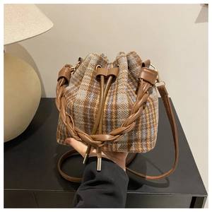 Detail of wool plaid bucket bag with woven handle and drawstring closure system