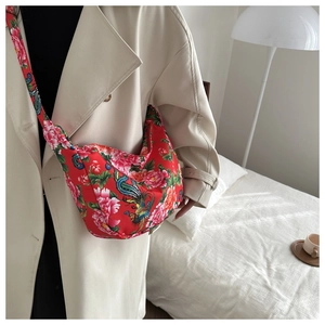 Détail du sac hobo rouge à motifs de pivoines porté sur l'épaule d'un mannequin