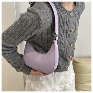 Side view of a light purple leather crescent bag featuring a FASHION logo on a female model