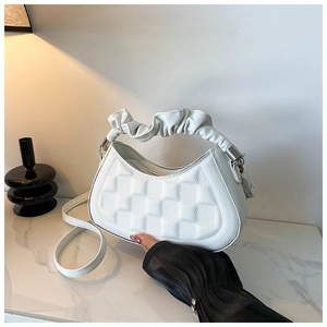 Detail view of white crescent bag with quilted pattern and ruched handle on marble