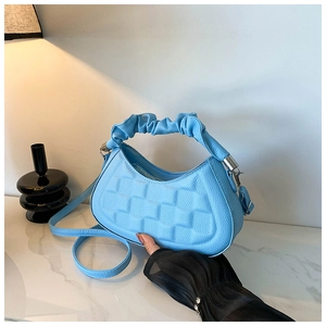 Detail of sky blue quilted crossbody bag with decorative pleated handle and lychee texture
