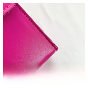 Macro shot of magenta leather texture and precise stitching on a minimalist square bag