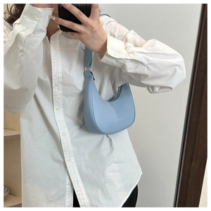 Detail of light blue hobo bag with fashion text and silver buckle on adjustable strap