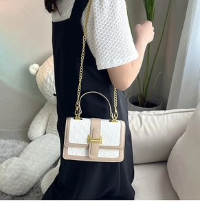 Détail du motif tissé blanc avec boucle H dorée et bandoulière chaîne sur le sac à main