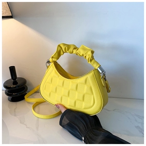 Detail of yellow baguette bag with embossed checkered pattern and ruched handle