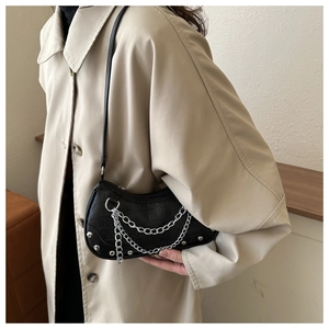 Close-up of black crocodile pattern half-moon shoulder bag with silver chain and studs