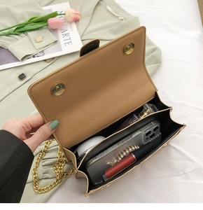 Détail intérieur du sac bandoulière kaki contenant téléphone, rouge à lèvres et parfum