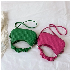 Top view of emerald green and rose pink pleated hobo bags on white fabric background