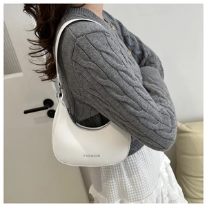 Detail of white moon-shaped shoulder bag featuring 'FASHION' text and smooth leather texture