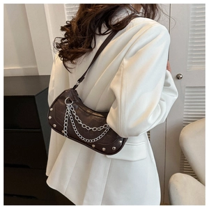Detail of dark brown crocodile texture underarm bag with silver chain and rivet accents