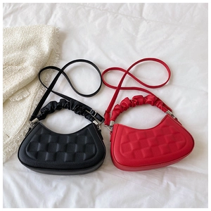 Flat lay of red and black textured half-moon bags with embossed square patterns
