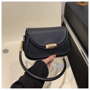 Détail d'un sac à main en cuir noir avec boucle dorée à triple anneau et bandoulière