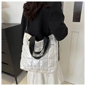 Macro detail of silver quilted puffer tote bag with black straps and metallic finish