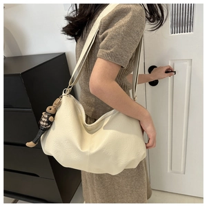 Detail of cream white pleated dumpling bag featuring a cute bunny pendant accessory