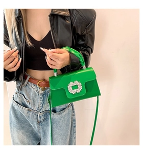 Detail of a bright green PU leather handbag with a large sparkling rhinestone square buckle
