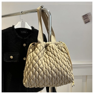 Detail of beige quilted tote bag featuring drawstring closure and textured bubble pattern