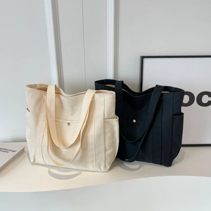 Large canvas tote bags in cream and black with functional side pockets and magnetic buckles