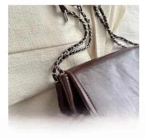 Close-up of the vintage brown faux leather texture and silver chain strap detail on handbag