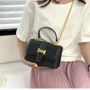 Sac à main en cuir gaufré noir avec surpiqûres blanches et bandoulière chaîne dorée