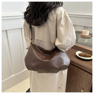 Detail der dunkelbraunen Hobo-Tasche aus Kunstleder mit weichen Falten, getragen von Model