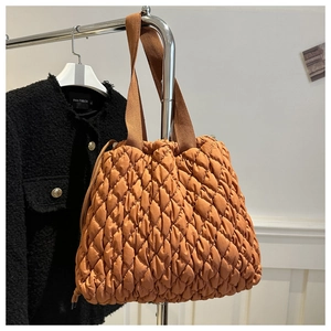 Detail of caramel brown quilted tote bag with soft puffer texture and wide shoulder strap
