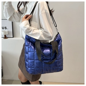 Detail of blue metallic quilted tote bag showing wide straps and detachable crossbody strap
