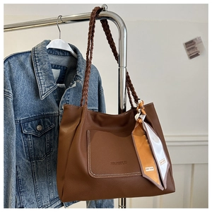 Makro-Detail der braunen Leder-Tote-Bag mit Seidenschal und gewebtem Schultergurt