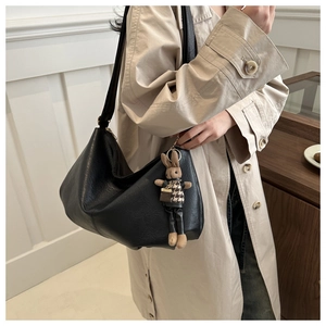 Detail of black large capacity hobo bag with a cute plaid rabbit charm on a trench coat
