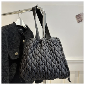 Detail of black quilted puffer tote bag featuring textured honeycomb pattern and drawstring