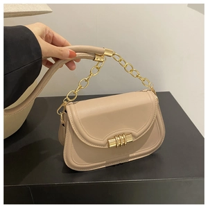Détail du sac beige avec rabat à bordure ondulée et boucle métallique dorée en spirale