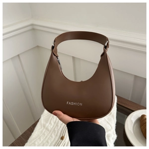 Detail view of brown crescent shoulder bag with white fashion text and soft leather texture